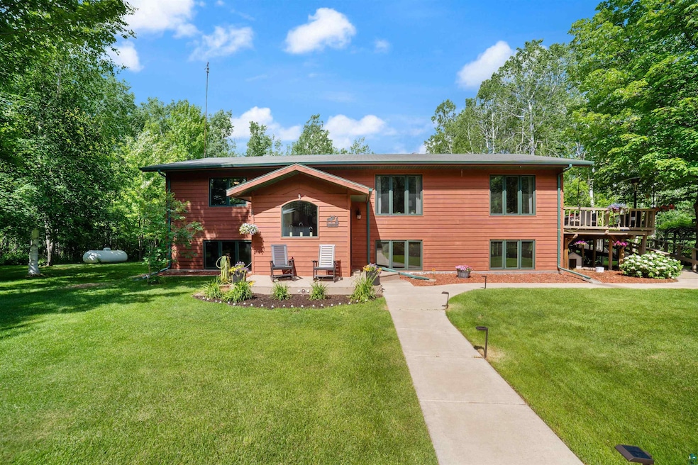 Bi-level home with a front lawn, a wooden deck, and a patio area
