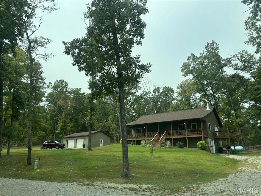 View of front facade with a garage, an outdoor structure, a front lawn, stairs, and a porch