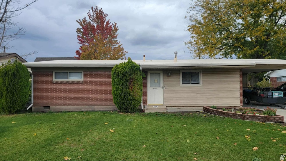 Ranch-style home with a front yard, brick siding, and an attached carport