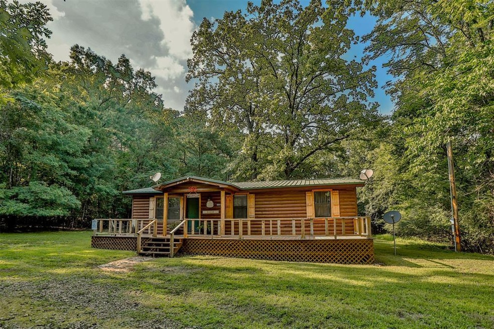 Cabin with a front lawn and a wooden deck