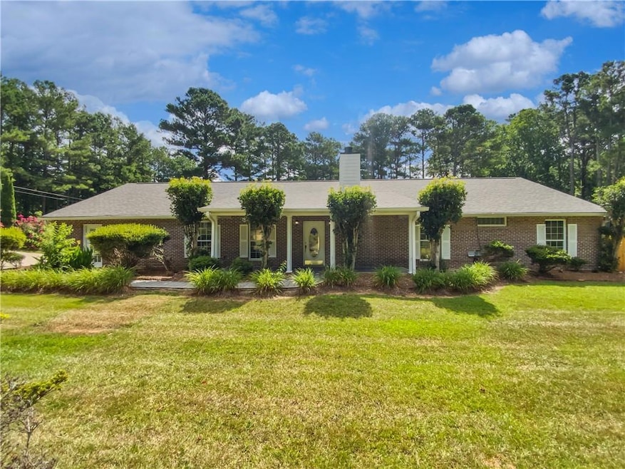 Ranch-style home with brick siding, a chimney, and a front yard