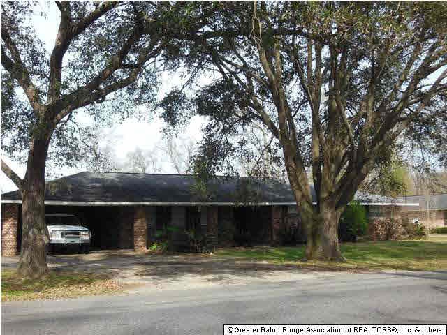 Front of home shaded by live oaks.