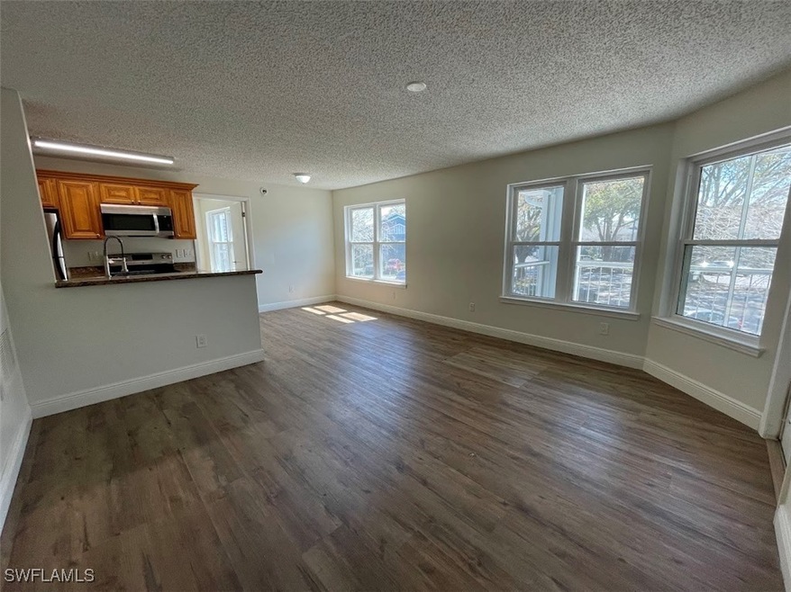 Unfurnished living room with baseboards, dark wood