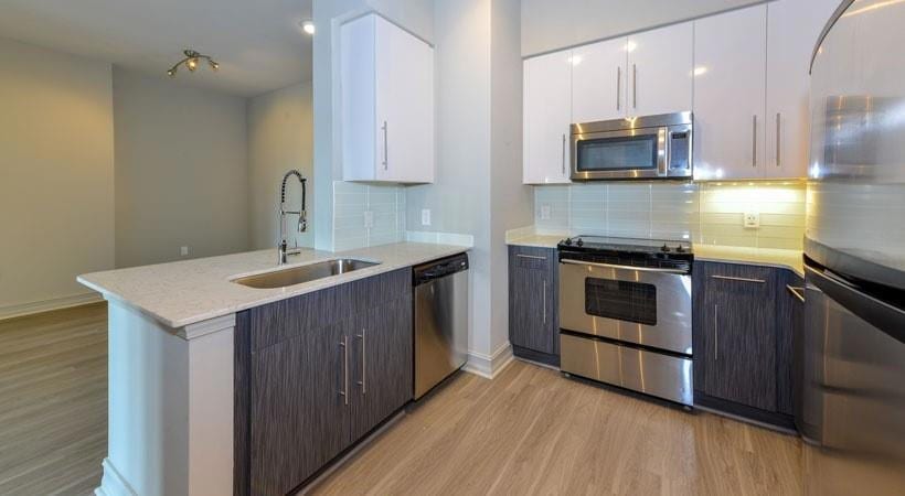 Kitchen with sink, light wood-type flooring, stainless steel appliances, and white cabinets