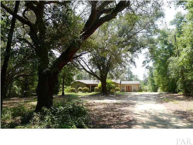 Country home tucked away on 13 acres in the heart of Pace.