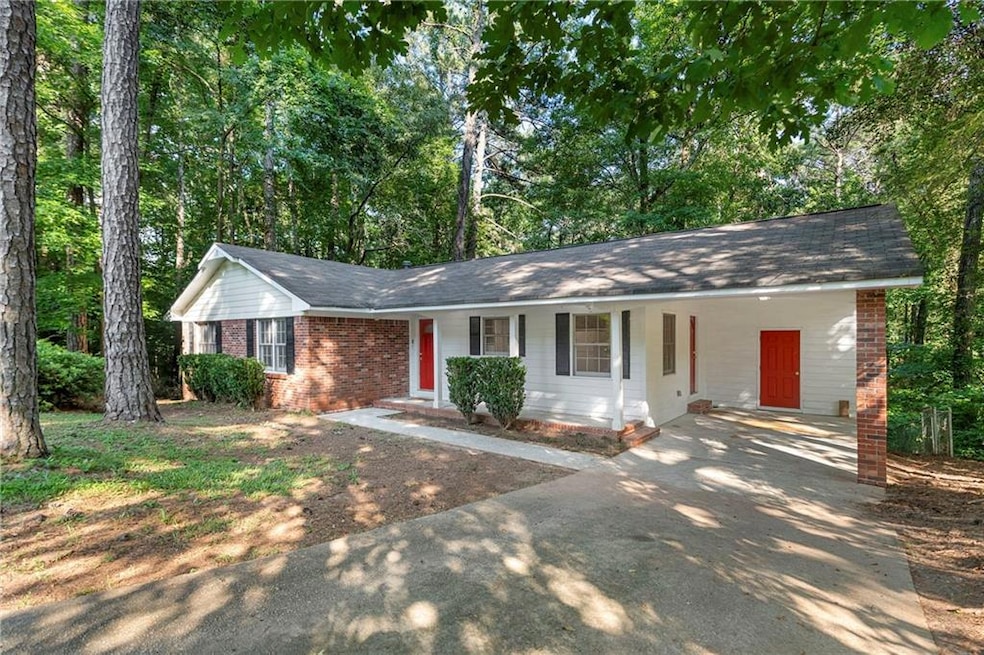 Single story home featuring brick siding, an attached carport, covered porch, a shingled roof, and concrete driveway