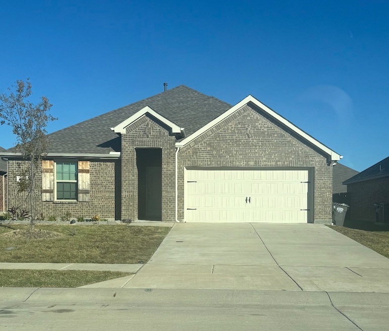 Ranch-style home featuring brick siding, an attached garage, driveway, and roof with shingles