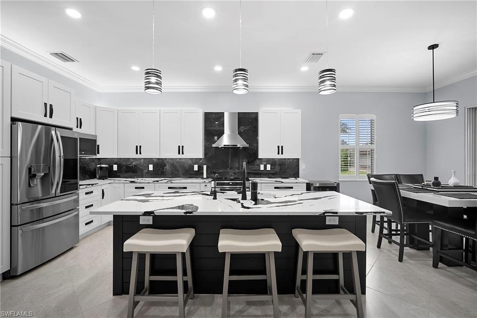 Kitchen with ornamental molding, backsplash, a breakfast bar area, appliances with stainless steel finishes, and decorative light fixtures
