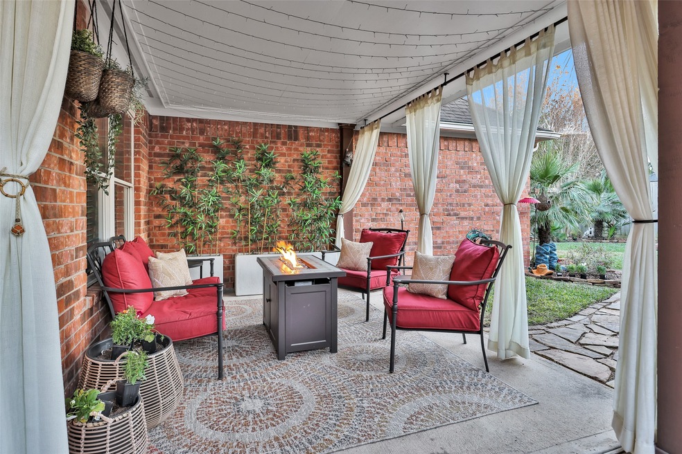 Charming covered patio features lush greenery, str