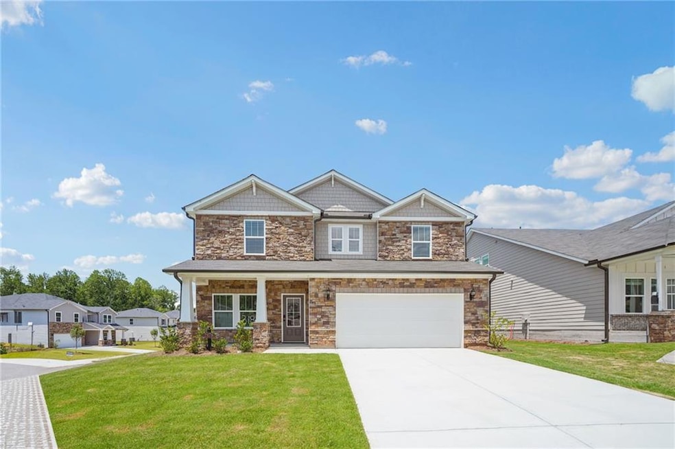 Craftsman inspired home with stone siding, a front lawn, driveway, and a garage