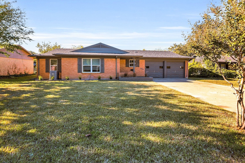 Single story home featuring brick siding, driveway, a front yard, a garage, and roof with shingles