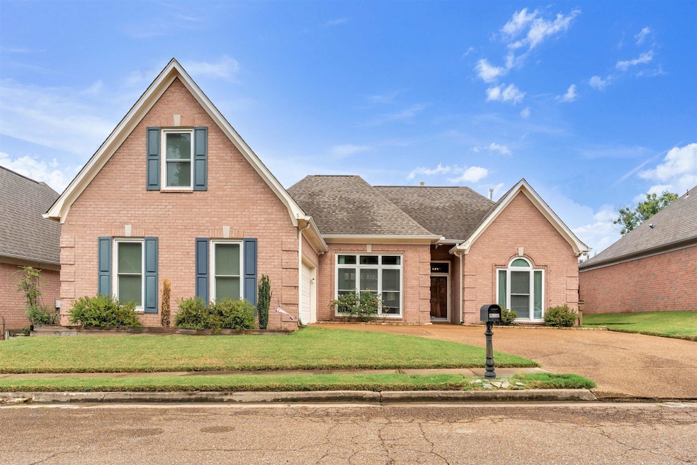Traditional home with a shingled roof, brick siding, and a front yard