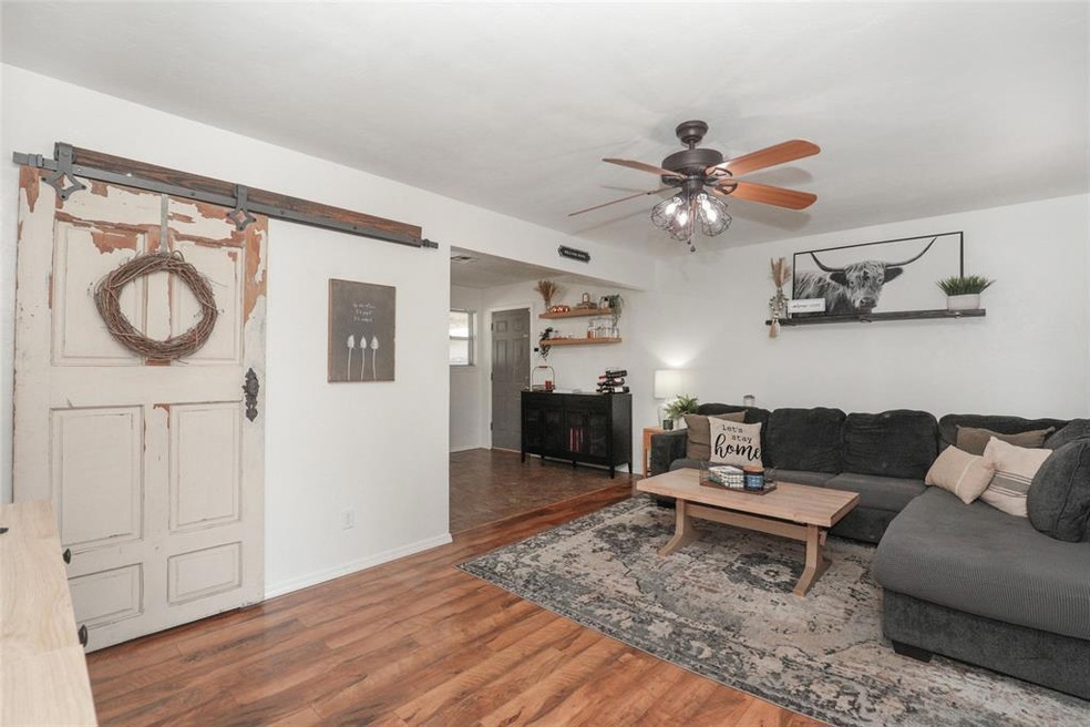 Living room featuring a barn door, ceiling fan, an
