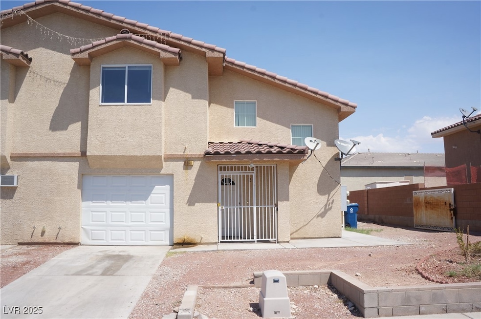 Rear view of property featuring stucco siding, driveway, a tiled roof, and an attached garage