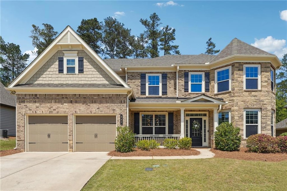 View of front facade with central air condition unit, driveway, a porch, an attached garage, and a front yard