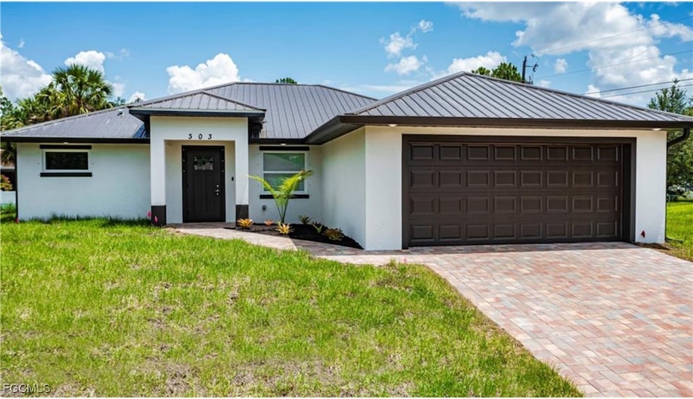 View of front of house featuring stucco siding, a front yard, a garage, and decorative driveway
