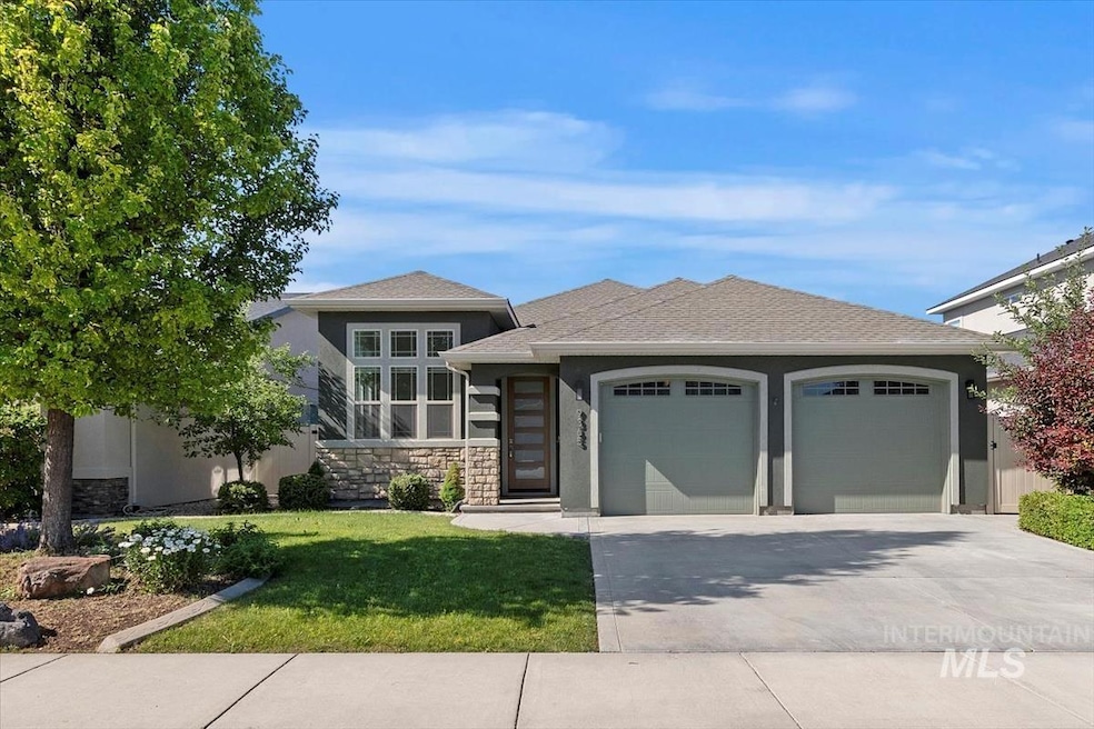 View of front of property featuring a garage, stone siding, stucco siding, concrete driveway, and a front lawn