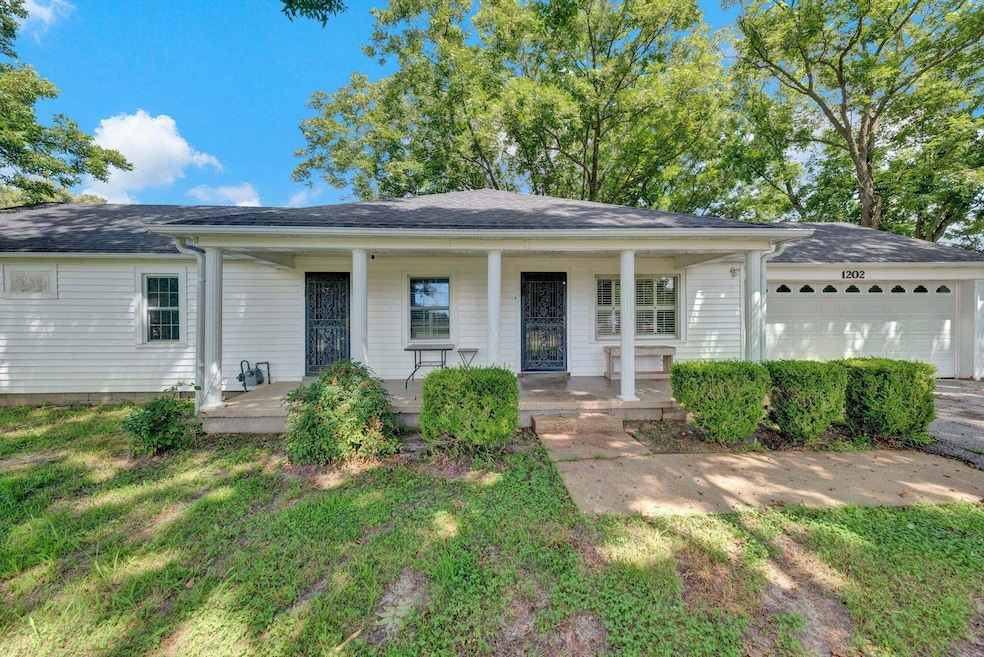 Ranch-style home featuring a porch, an attached garage, and a front yard