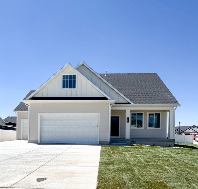 View of front facade with board and batten siding, roof with shingles, driveway, and an attached garage