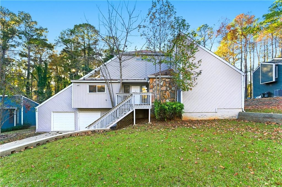 View of front of property featuring a front lawn, stairs, a deck, driveway, and an attached garage