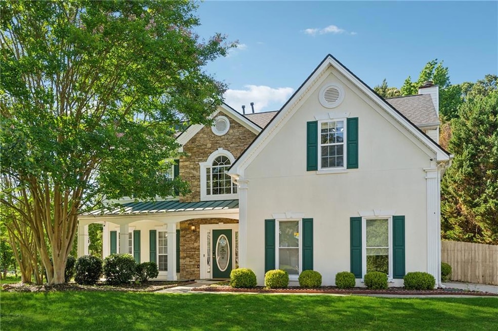 View of front of house with a chimney, a standing seam roof, metal roof, a shingled roof, and stucco siding
