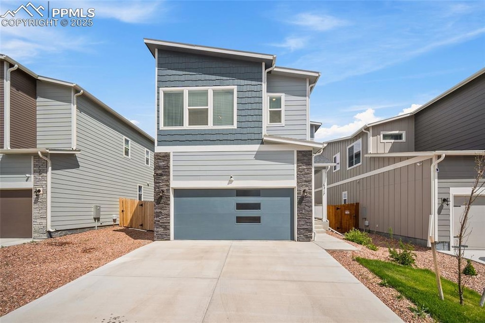 Modern home featuring stone siding, an attached garage, and concrete driveway