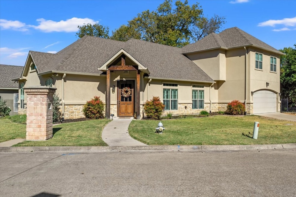View of front of home featuring stone siding, a front lawn, and stucco siding