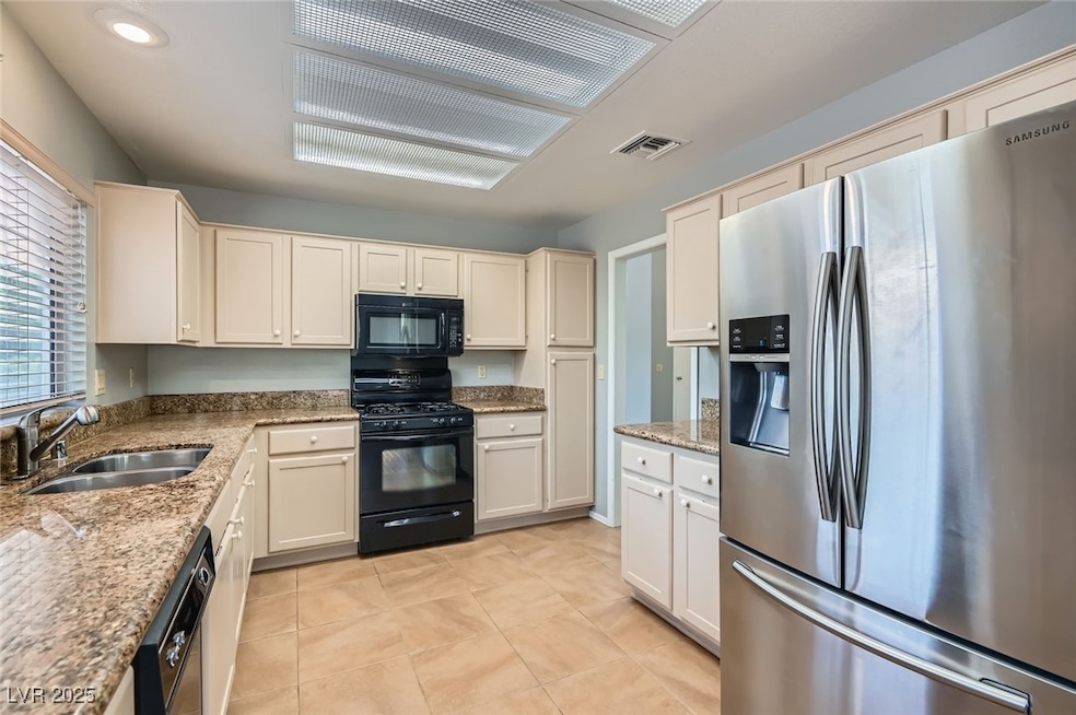 Kitchen featuring black appliances, light stone co