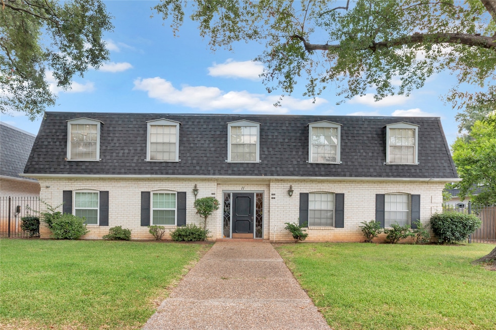 Front of property featuring mansard roof, roof with shingles, and brick siding