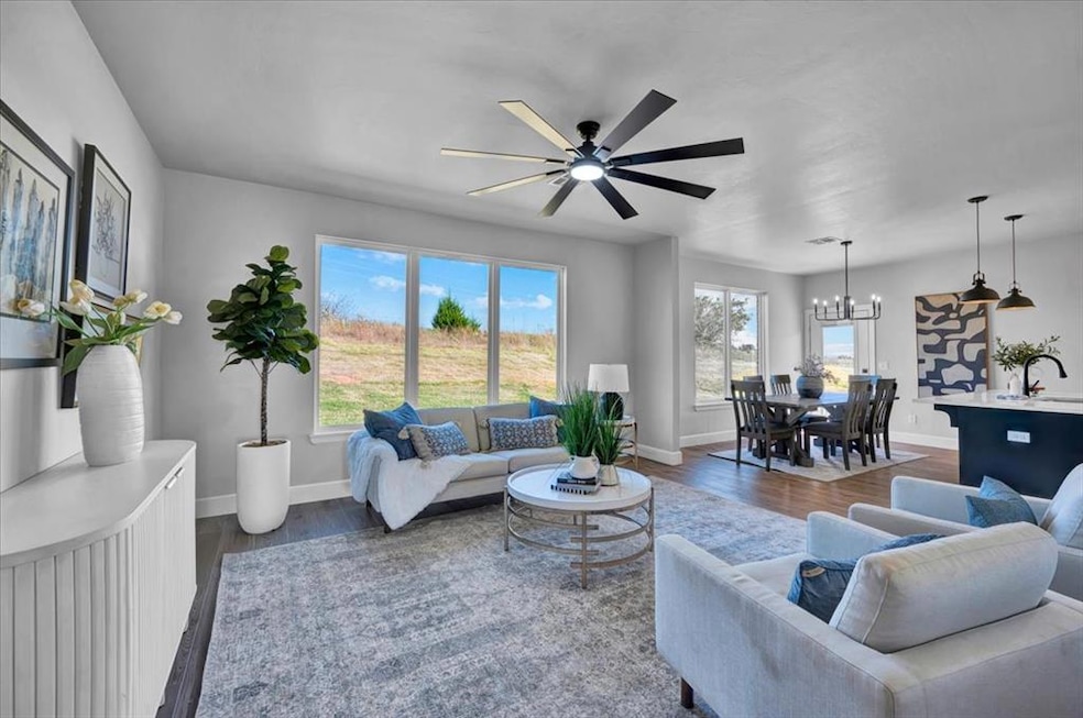 Living area with dark wood-type flooring, ceiling fan, and a chandelier
