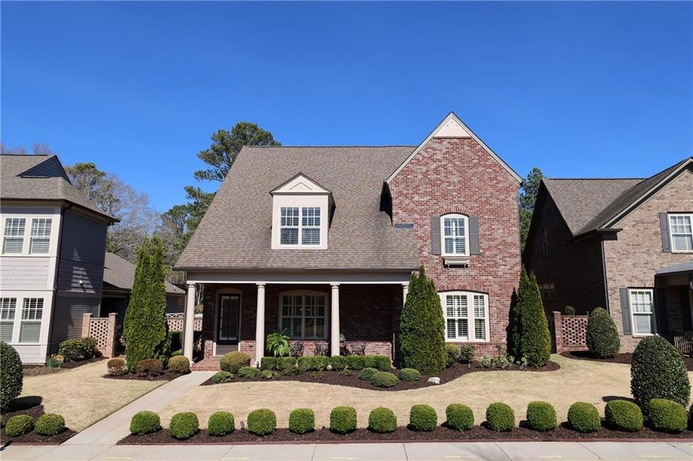 Brick home with charming front porch and iron entry gate to side yard.