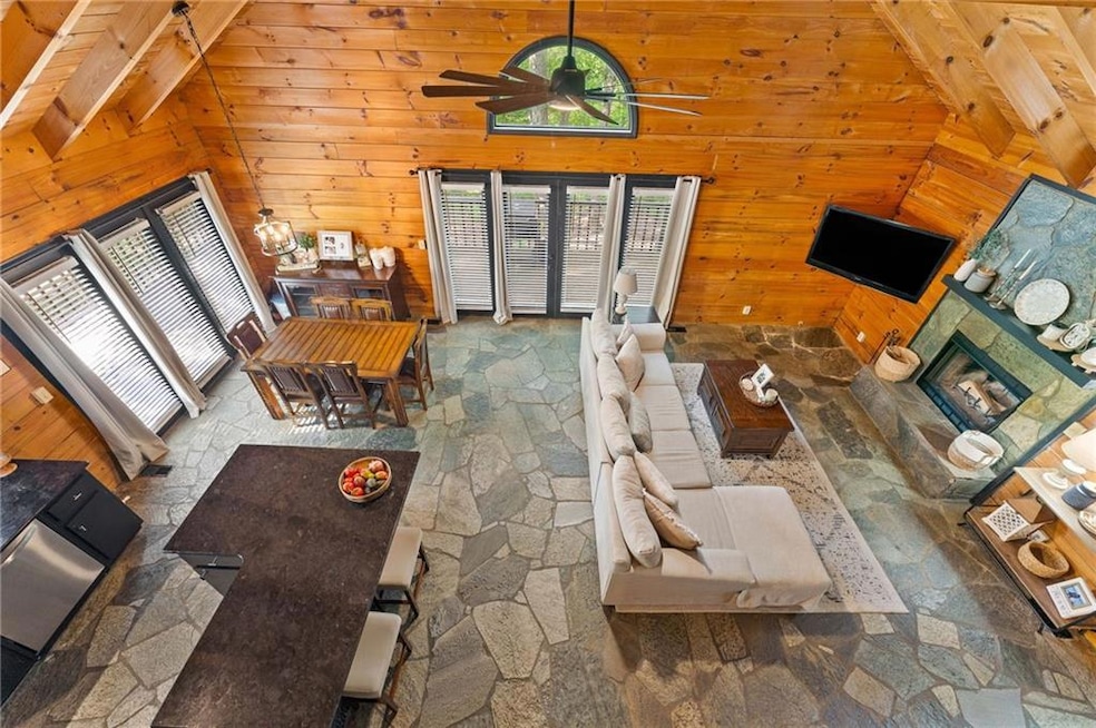 Living area with plenty of natural light, stone tile floors, wood walls, and a ceiling fan