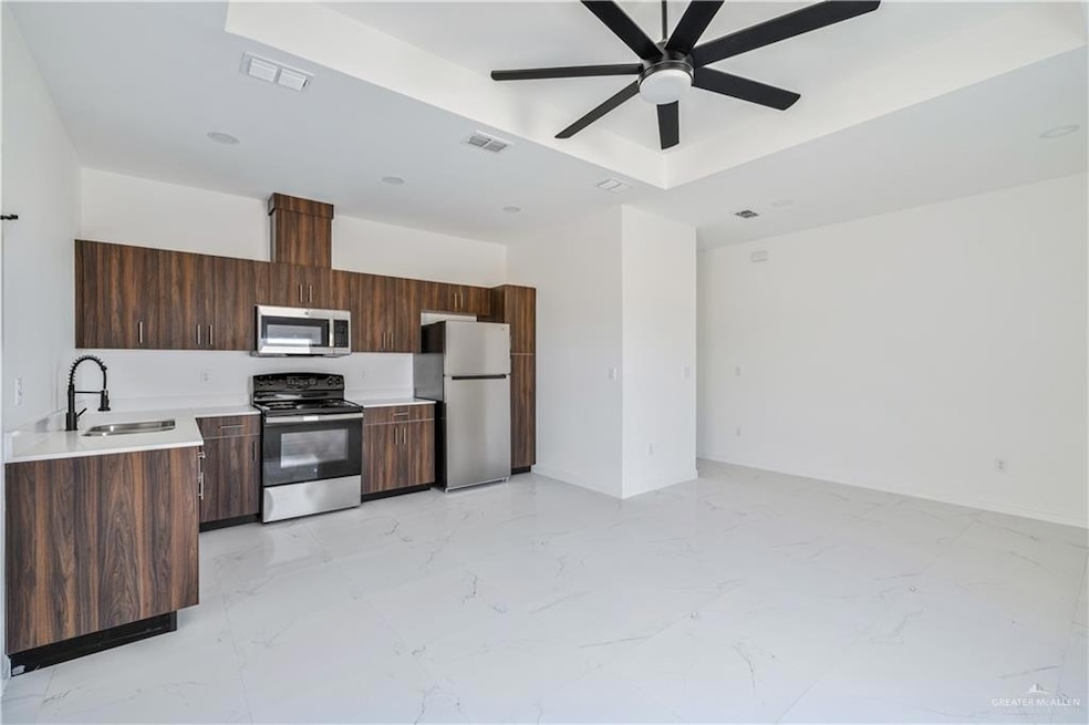 Kitchen with appliances with stainless steel finishes, light countertops, modern cabinets, a ceiling fan, and light marble finish flooring