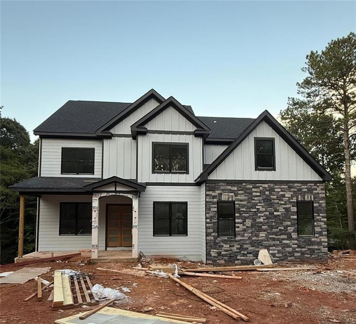 View of front of property featuring board and batten siding, a porch, and roof with shingles