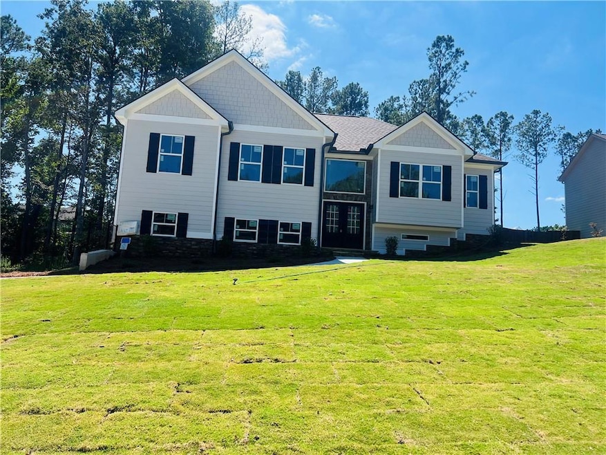 Split foyer home with a front lawn and stone siding