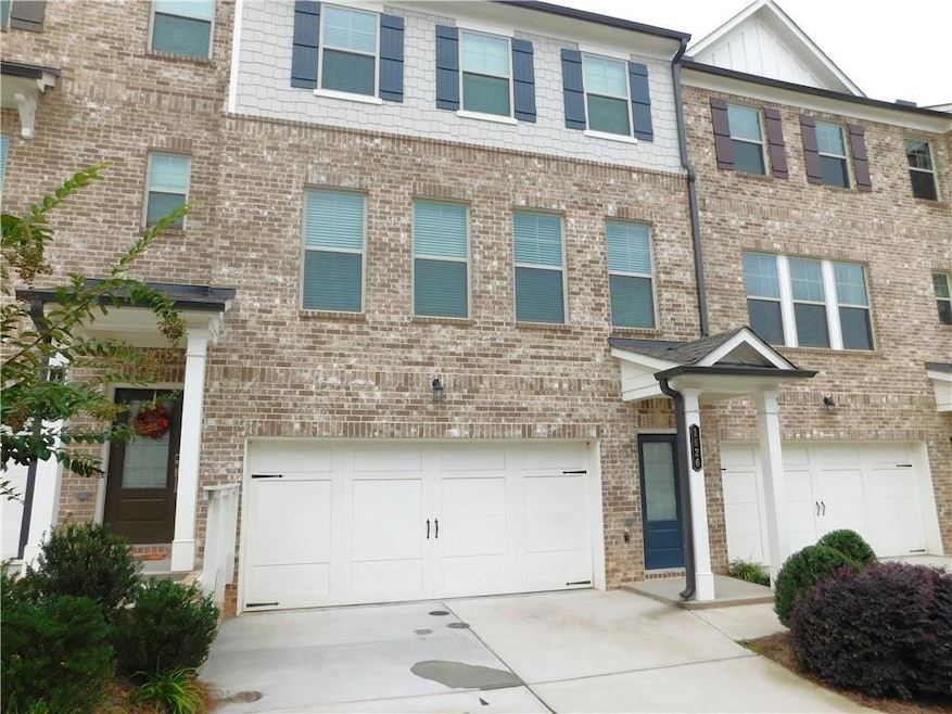 View of front of property featuring driveway, brick siding, and a garage