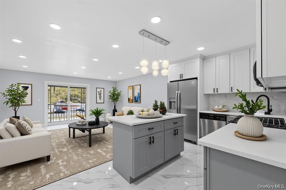 Kitchen with open floor plan, light marble finish flooring, appliances with stainless steel finishes, hanging light fixtures, and recessed lighting