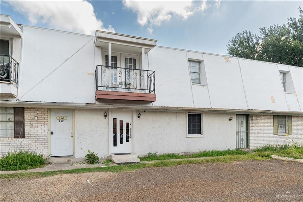 View of front of home with a balcony, stucco siding, and brick siding