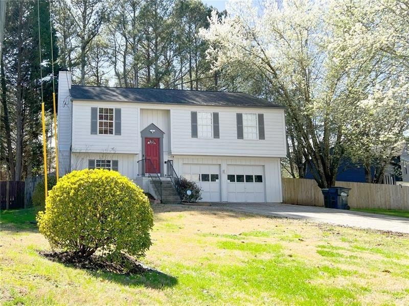 Raised ranch featuring driveway, an attached garage, and a chimney