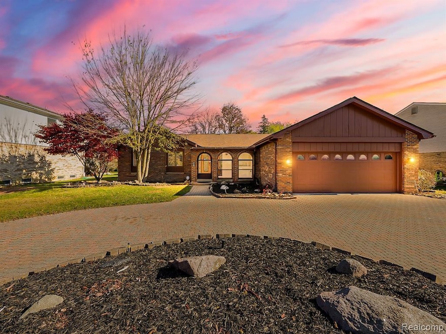 View of front of property with decorative driveway, a garage, board and batten siding, and a front yard