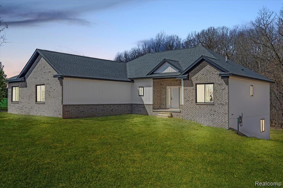 View of front of house featuring a yard, brick siding, and roof with shingles