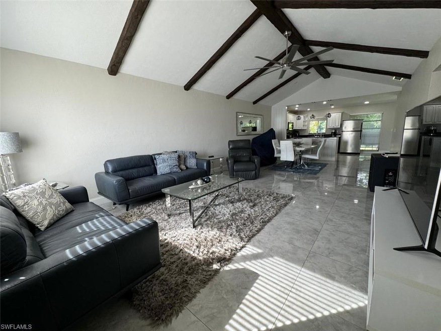 Spacious and light-filled, featuring soaring vaulted ceilings with wood beams, modern tile flooring, and open flow to the dining and kitchen areas — ideal for everyday living and entertaining.