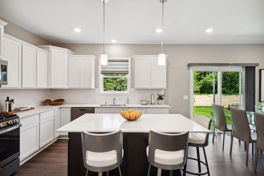 This spacious kitchen features a large center island, quartz countertops, recessed lighting, LVP wood floors, stainless appliances and more! (Model photo)