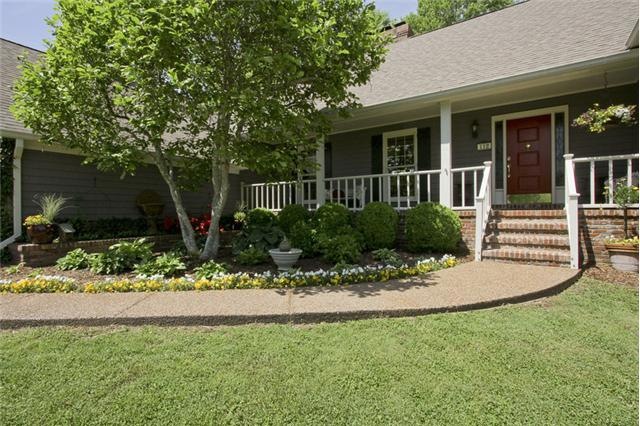 Gracious front entry with inviting covered porch and welcoming perennial garden with fountain.