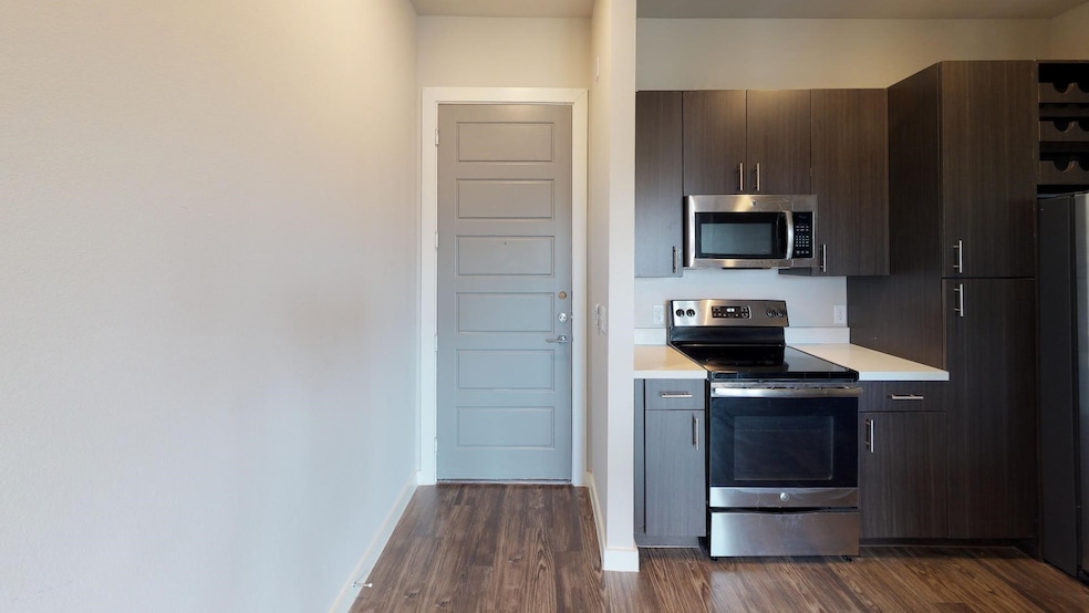 Kitchen with dark brown cabinets, stainless steel appliances, and dark hardwood / wood-style flooring