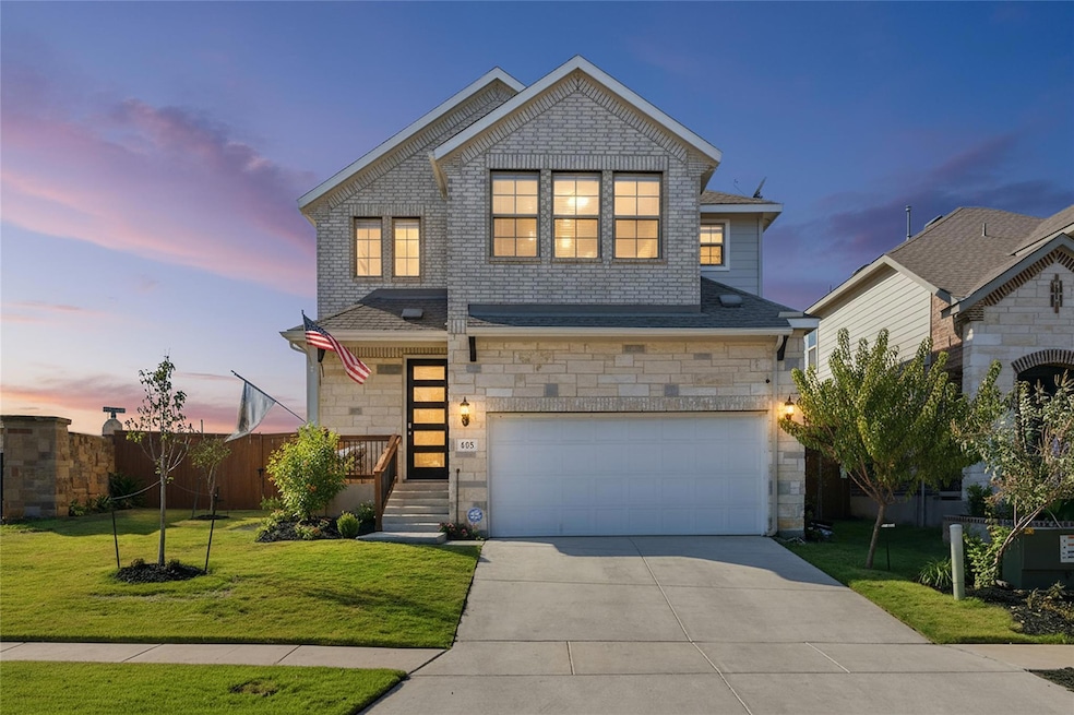 View of front of house with stone siding, driveway, and a garage