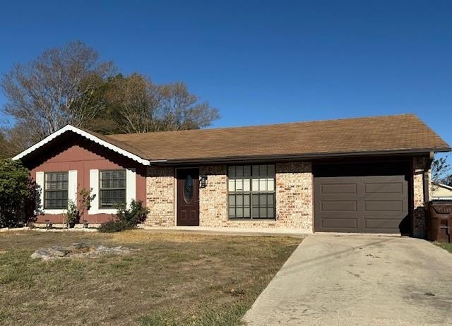 Ranch-style home featuring concrete driveway, an attached garage, a front yard, and roof with shingles