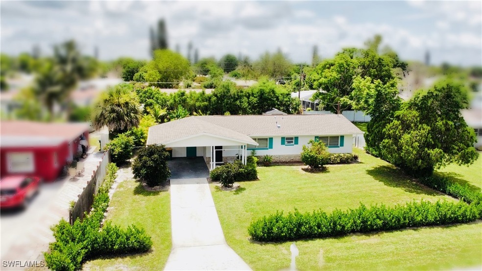 View of front of home with a carport, driveway, a front yard, and stucco siding