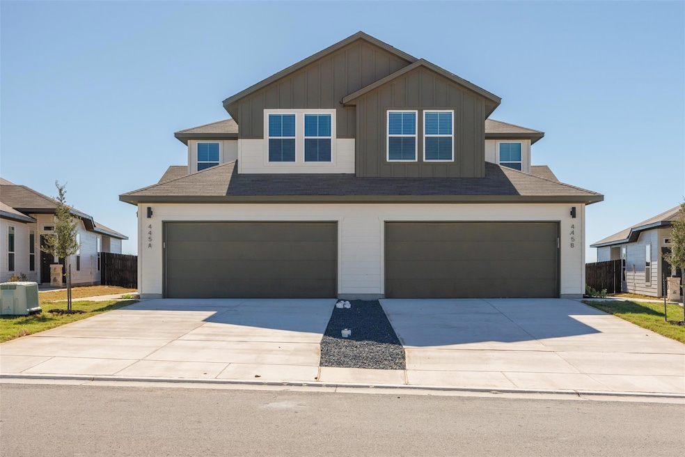 View of front of property with board and batten siding, driveway, a garage, and roof with shingles