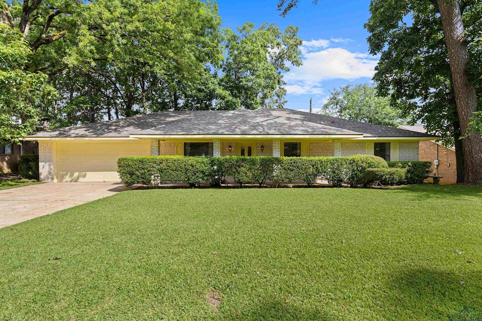 Ranch-style home with a garage, brick siding, a front lawn, and driveway